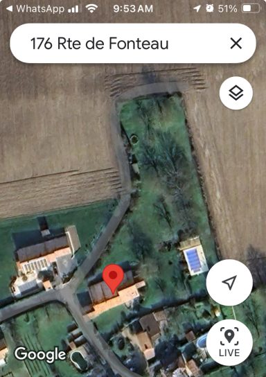 Luchtfoto van een woning en omliggende grond met wegen en groenvoorzieningen.