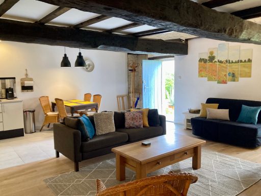 Modern woonkamer met banken, houten balken en toegang tot een buitenruimte.
