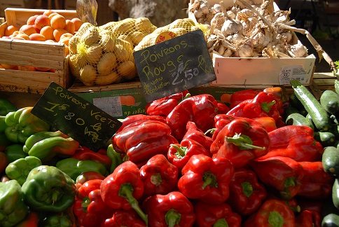 Kleurige groenten en fruit op een markt, waaronder paprika's, citroenen en paddenstoelen.