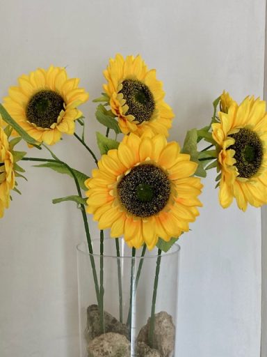 Een vaas met zonnebloemen tegen een lichte achtergrond.